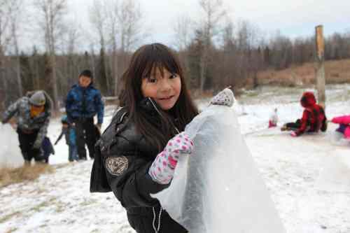 Ruth Bonneville / Winnipeg Free Press
Kids use scrap sheets of plastic to slide down a hill next to their home.