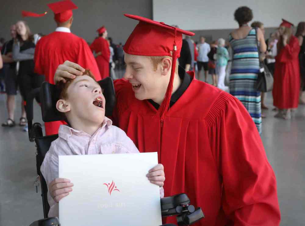 Griffin shares a touching moment with his younger brother, Tyler who has cerebral palsy, after receiving his diploma at his convocation ceremony.  (Ruth Bonneville / Winnipeg Free Press)