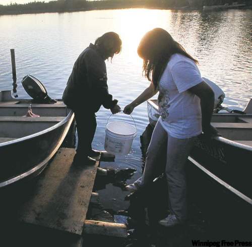 JOE.BRYKSA@FREEPRESS.MB.CA 
Annie Dan (left) and Annabella Dan collect lake water at Red Sucker Lake.