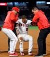 Los Angeles Angels' Andrelton Simmons, center, is helped up by manager Brad Ausmus, left, and a trainer after he was injured while being thrown out at first during the eighth inning of a baseball game against the Minnesota Twins Monday, May 20, 2019, in Anaheim, Calif. (AP Photo/Mark J. Terrill)