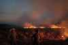 Leo Correa / The Associated Press
Neri dos Santos Silva, center, watches an encroaching fire threat on Friday after digging trenches to keep the flames from spreading to the farm he works on.