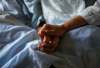 A woman holds the hand of her mother who is dying from cancer during her final hours at a palliative care hospital in Winnipeg.