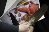 A woman holds a photo of a baby and an eagle feather at a press conference in support of the mother who's newborn baby was seized from hospital by Manitoba's Child and Family Services (CFS) at First Nations Family Advocate Office in Winnipeg on Friday, January 11, 2019. The family of a newborn seen in a social media video being taken away by police in hospital will be back in court next month in an effort to get the baby back. THE CANADIAN PRESS/John Woods