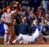 Chicago Cubs' Kris Bryant, right, scores as Philadelphia Phillies' J.T. Realmuto, left, waits for the ball during the ninth inning of a baseball game, Tuesday, May 21, 2019, in Chicago. (AP Photo/Kamil Krzaczynski)