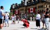 Canadian flags are seen on the Office of the Prime Minister and Privy Council as tourists take photos on Parliament Hill before Canada Day, in Ottawa on Thursday, June 27, 2019. THE CANADIAN PRESS/Justin Tang