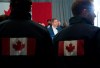 Conservative staff members wearing jackets with the Canadian flag on them look on as Conservative leader Andrew Scheer addresses the media during a morning announcement during a campaign stop in Toronto Friday, October 4, 2019. THE CANADIAN PRESS/Jonathan Hayward