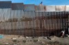 FILE - In this Nov. 21, 2018, file photo, a homeless man walks next to the fence that divides Mexico and the U.S, in Tijuana, Mexico. The Trump administration expects to launch a policy as early as Friday, Jan. 25, 2019, that forces people seeking asylum to wait in Mexico while their cases wind through U.S. courts, an official said, marking one of the most significant changes to the immigration system of Donald Trump's presidency. (AP Photo/Rodrigo Abd, File)