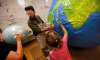 Art City’s art director Eddy Ayoub (centre) looks for references on an actual globe, while 8-year-old Emma Loshakova paints Cuba on a giant paper mâché globe Tuesday afternoon preparing to participate in the Global Climate Strike to be held here on Friday. (Phil Hossack / Winnipeg Free Press)