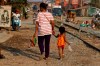 FILE - In this Jan. 29, 2019, file photo a garment worker walks with her child from the factory after her shift in Phnom Penh, Cambodia. In a report Tuesday, Oct. 8, the World Bank warns that trade conflicts between major countries, specifically the United States and China, are disrupting supply chains and causing manufacturers to delay investment decisions to avoid getting caught in a trade-war crossfire. (AP Photo/Heng Sinith, File)