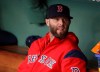 FILE - In this Tuesday, April 30, 2019, file photo, Boston Red Sox's Dustin Pedroia sits in the dugout prior to a baseball game at Fenway Park, in Boston. Pedroia is hoping to return to the Boston Red Sox in 2020 after playing in just nine games during the past two seasons because of his injured left knee. (AP Photo/Charles Krupa, File)