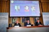 Goran K Hansson, centre, Secretary General of the Royal Swedish Academy of Sciences, and academy members Mats Larsson, left, and Ulf Danielsson, announce the winners of the 2019 Nobel Prize in Physics, during news conference at the Royal Swedish Academy of Sciences in Stockholm, Sweden, on Tuesday Oct. 8, 2019. The 2019 Nobel Prize in Physics is awarded to, seen from left on the screen, James Peebles, Michel Mayor and Didier Queloz. (Claudio Bresciani / TT via AP)