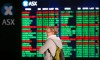 A woman looks at display boards at the Australian Stock Exchange in Sydney, Australia, Monday, May 6, 2019. Shares tumbled in Asia after President Donald Trump threatened to impose more tariffs on China, spooking investors who had been expecting good news this week on trade. (AP Photo/Rick Rycroft)