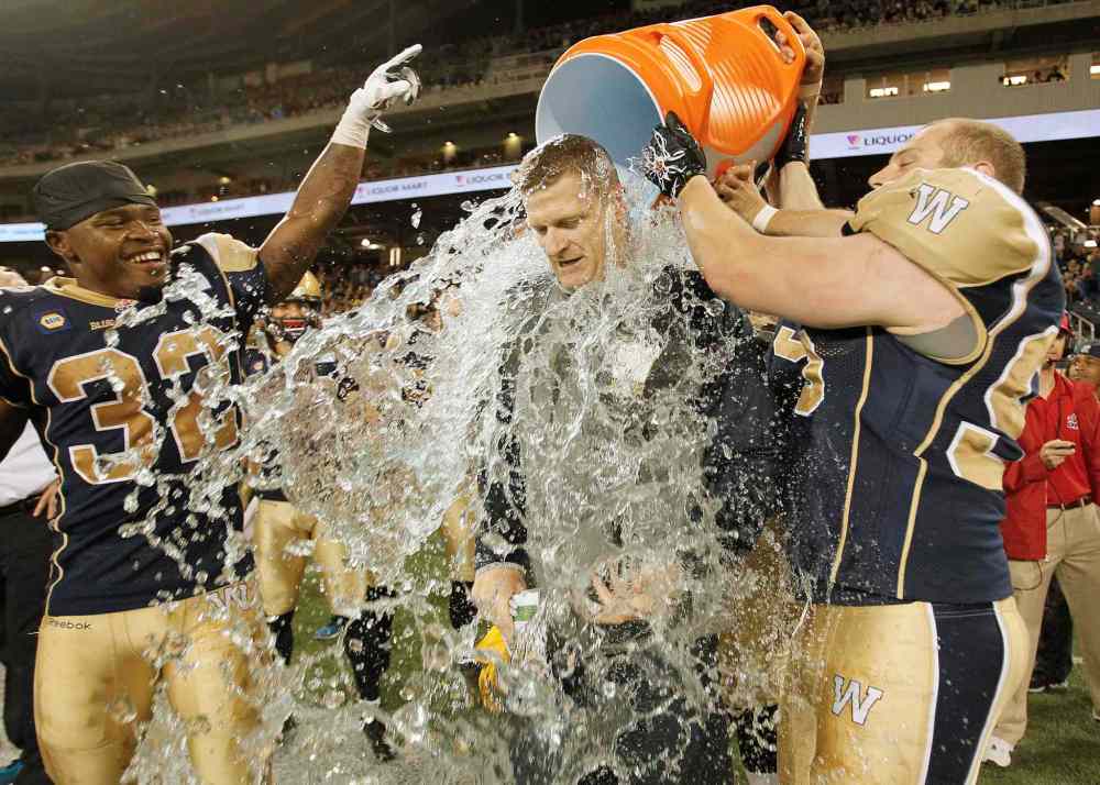 Winnipeg Blue Bombers Nic Grigsby (32) and Jake Thomas (95) celebrate head coach Mike O'Shea's first win as their new coach in CFL action against Toronto Argonauts in Winnipeg Thursday, June 26, 2014. (John Woods / The Canadian Press files)