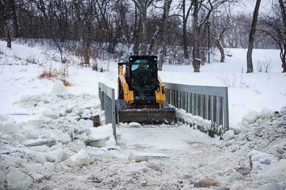 A sub-contractor works on making the ice at the edges of the path less sharp at the Omand's Creek bridge which had been closed by the city and subsequently cleared of snow and ice by local Wolseley residents. (Mikaela MacKenzie)