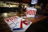 A server collects a food order beside a mock polling station for patrons as they watch US election returns at The Unicorn bar Calgary on Tuesday, Nov. 3, 2020. THE CANADIAN PRESS/Jeff McIntosh