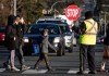 A crossing guard stops traffic as students wearing face masks to curb the spread of COVID-19 arrive at Ecole Woodward Hill Elementary School, in Surrey, B.C., on Tuesday, Feb.23, 2021. THE CANADIAN PRESS/Darryl Dyck