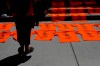 A woman looks over orange shirts, shoes, flowers and messages displayed on the steps outside the legislature in Victoria on Tuesday, June 8, 2021 following a ceremony in honour of the 215 residential school children whose remains were detected near a former residential school at Kamloops, B.C. The Lower Kootenay Band in B.C.'s southern Interior says a search using ground-penetrating radar has also found the remains of 182 people in unmarked graves at another residential school site.THE CANADIAN PRESS/Chad Hipolito