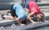 A boy and girl dunk their heads in a water fountain during a heat wave in Montreal, Monday, July 2, 2018. THE CANADIAN PRESS/Graham Hughes