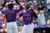 Colorado Rockies' Charlie Blackmon, left, congratulates C.J. Cron who crosses home plate after hitting a grand slam off Miami Marlins relief pitcher Sean Guenther in the fourth inning of a baseball game Sunday, Aug. 8, 2021, in Denver. (AP Photo/David Zalubowski)