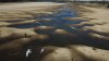 FILE - In this Thursday, July 29, 2021 file photo, birds fly over a man taking photos of the exposed riverbed of the Old Parana River, a tributary of the Parana River during a drought in Rosario, Argentina. Parana River Basin and its related aquifers provide potable water to close to 40 million people in South America, and according to environmentalists the falling water levels of the river are due to climate change, diminishing rainfall, deforestation and the advance of agriculture. (AP Photo/Victor Caivano, File)