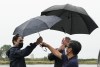 Liberal Leader Justin Trudeau, left, is handed an umbrella from his senior adviser Ben Chin while talking to climate scientist Andrew Weaver during a campaign stop in Steveston Harbour, Richmond, B.C., on Tuesday, Sept. 14, 2021. THE CANADIAN PRESS/Sean Kilpatrick