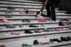 A woman places one of 215 pairs of children's shoes on the steps of the Vancouver Art Gallery as a memorial to the 215 children whose remains have been found buried at the site of a former residential school in Kamloops, in Vancouver, B.C., Friday, May 28, 2021. When the Tk'emlúps te Secwe̓pemc Nation announced the discovery of 215 unmarked graves found at the site of a former residential school in Kamloops, B.C., Canadians had to face the horrific realities Indigenous children and youth had to live while being forced to attend residential schools. THE CANADIAN PRESS/Darryl Dyck