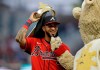Atlanta Braves left fielder Eddie Rosario removes a crown hat from his head beside Braves mascot 'Blooper' prior to a baseball game against the New York Mets, Friday, Oct. 1, 2021, in Atlanta. (AP Photo/Ben Margot)
