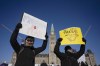 Protesters participating in a cross-country truck convoy protesting measures taken by authorities to curb the spread of COVID-19 and vaccine mandates hold signs on Parliament Hill in Ottawa on Saturday, Jan. 29, 2022. THE CANADIAN PRESS/Adrian Wyld