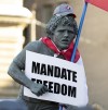 A statue of Terry Fox is decorated with a Canadian flag, protest sign and hat as protesters participating in a cross-country truck convoy protesting measures taken by authorities to curb the spread of COVID-19 and vaccine mandates gather on Parliament Hill in Ottawa, Saturday, Jan. 29, 2022. Some protesters jumped on the Tomb of the Unknown Soldier and others fastened an inverted Canadian flag to a statue of Terry Fox as they decried vaccine mandates in the nation's capital on Saturday. THE CANADIAN PRESS/Adrian Wyld