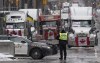 Police man a barricade in front of vehicles parked as part of the trucker protest, Tuesday, Feb. 8, 2022 in Ottawa’s downtown core. Ottawa's city manager says all tow-companies on contract with the city have refused to haul away the large trucks that have gridlocked Ottawa's downtown for the second week in a row.  THE CANADIAN PRESS/Adrian Wyld