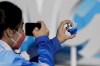 A woman takes a picture of the Olympic mascot, Bing Dwen Dwen, at the Olympic Green ahead of the 2022 Winter Olympics, Feb. 1, 2022, in Beijing. (AP Photo/Natacha Pisarenko)