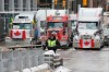 A police member stands in front of trucks blocking downtown streets as a rally against COVID-19 restrictions, which began as a cross-country convoy protesting a federal vaccine mandate for truckers, continues in Ottawa, on Wednesday, February 9, 2022. THE CANADIAN PRESS/ Patrick Doyle