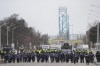 Police walk the line to remove all truckers and supporters after a court injunction gave police the power to enforce the law after protesters blocked the access leading from the Ambassador Bridge, linking Detroit and Windsor, as truckers and their supporters continue to protest against COVID-19 vaccine mandates and restrictions, in Windsor, Ont., Sunday, Feb. 13, 2022. The Canada Border Services Agency says the AmbassadorBridge border crossing between Windsor, Ont., and Detroit has reopened.  THE CANADIAN PRESS/Nathan Denette