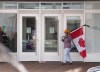 A man speaks on a cellphone while carrying a hockey stick draped with the Canadian flag in front of the Fredericton Convention Centre to protest against COVID-19 public health measures, on Saturday, Feb. 12, 2022.THE CANADIAN PRESS/Aaron Sousa