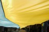 A child walks under a large Ukrainian flag carried by people marking a 