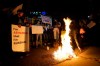 A Russian citizen burns a Russian flag as people protest the Russian invasion of Ukraine at a demonstration in the Studio City neighborhood of Los Angeles, Thursday, Feb. 24, 2022. (AP Photo/Damian Dovarganes)