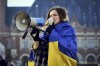 A woman is wrapped in the Ukrainian flag and shouts through a megaphone during a demonstration in front of the International Criminal Court in The Hague, Netherlands, Monday, March 7, 2022. A representative for Kyiv has urged the United Nations' top court to order Russia to halt its devastating invasion of Ukraine, at a hearing snubbed by Russia. (AP Photo/Phil Nijhuis)