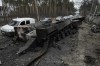 FILE - Cars drive past a destroyed Russian tank as a convoy of vehicles evacuating civilians leaves Irpin, on the outskirts of Kyiv, Ukraine, March 9, 2022. Thousands of patients in Ukraine are receiving lifesaving medicines to treat HIV and opioid addiction through a U.S.-funded group still operating despite the Russian invasion. Supplies are running short and making deliveries is a complicated calculus with unpredictable risks. (AP Photo/Vadim Ghirda, File)