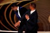 Will Smith, right, hits presenter Chris Rock on stage while presenting the award for best documentary feature at the Oscars on Sunday, March 27, 2022, at the Dolby Theatre in Los Angeles. (AP Photo/Chris Pizzello)