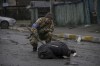 A Ukrainian serviceman checks the dead body of a civilian for booby traps in the formerly Russian-occupied Kyiv suburb of Bucha, Ukraine, Saturday, April 2, 2022. As Russian forces pull back from Ukraine's capital region, retreating troops are creating a 