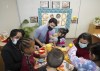 Canadian Prime Minister Justin Trudeau, back centre, plays with children in a daycare centre after reaching an agreement on $10-a-day child-care with Ontario Premier Doug Ford, not pictured, in Brampton, Ont., Monday, March 28, 2022. Feminist advocates say the budget doesn't fully account for the challenges in scaling up child-care systems across the country. THE CANADIAN PRESS/Nathan Denette