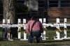 Pastor Daniel Myers kneels in front of crosses bearing the names of Tuesday's shooting victims while praying for them at Robb Elementary School in Uvalde, Texas, Thursday, May 26, 2022. (AP Photo/Jae C. Hong)