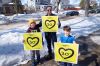 Ian Walke with his two sons, Owen (left) and Max (right) hold signs on Thursday in support of 30 km/h speed limits in residential zones. (Mike Sudoma / Winnipeg Free Press)