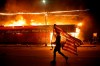 A protester carries a U.S. flag upside, a sign of distress, next to a burning building Thursday, May 28, 2020, in Minneapolis. Protests over the death of George Floyd, a black man who died in police custody Monday, broke out in Minneapolis for a third straight night. THE CANADIAN PRESS/AP-Julio Cortez