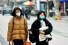 Women wear face masks as they walk down a street in Hangzhou in eastern China's Zhejiang province, Tuesday, Jan. 21, 2020. Face masks sold out and temperature checks at airports and train stations became the new norm as China strove Tuesday to control the outbreak of a new coronavirus that has reached four other countries and territories and threatens to spread further during the Lunar New Year travel rush. (Chinatopix via AP)