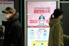 People pass by a poster warming about a new coronavirus at Suseo Station in Seoul, South Korea, Friday, Jan. 24, 2020. China broadened its unprecedented, open-ended lockdowns to encompass around 25 million people Friday to try to contain a deadly new virus that has sickened hundreds, though the measures' potential for success is uncertain. The sign reads 