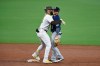 San Diego Padres' Fernando Tatis Jr. (23) hugs Seattle Mariners shortstop Dylan Moore (25) after hitting a double during the third inning of a baseball game Saturday, Sept. 19, 2020, in San Diego. (AP Photo/Denis Poroy)