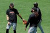 San Francisco Giants' Mauricio Dubon, left, smiles while talking with Johnny Cueto, bottom, and assistant coach Antoan Richardson during baseball practice in San Francisco, Tuesday, July 14, 2020. (AP Photo/Jeff Chiu)