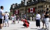 Canadian flags are seen on the Office of the Prime Minister and Privy Council as tourists take photos on Parliament Hill before Canada Day, in Ottawa on June 27, 2019. Canada's tourism industry is bracing for the possible impact of the novel coronavirus on the number of visitors to the country this summer travel season. Some experts are already seeing a change in the number of people coming to Canada from overseas, particularly from China -- the second largest long-haul market for Canada-bound tourists and the epicentre of the coronavirus outbreak. THE CANADIAN PRESS/Justin Tang