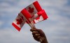 CP
A volunteer waves Canadian flags while handing them out to people during Canada Day festivities in Vancouver, B.C., on Monday, July 1, 2013. COVID-19 means the true north is not entirely free this Canada Day, but a new survey suggests that's not going to change how many people mark the holiday. THE CANADIAN PRESS/Darryl Dyck